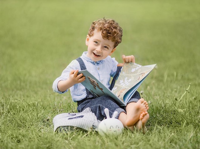 Ilustrační foto: dítě čte na louce